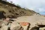 beach with fallen rocks and static homes above