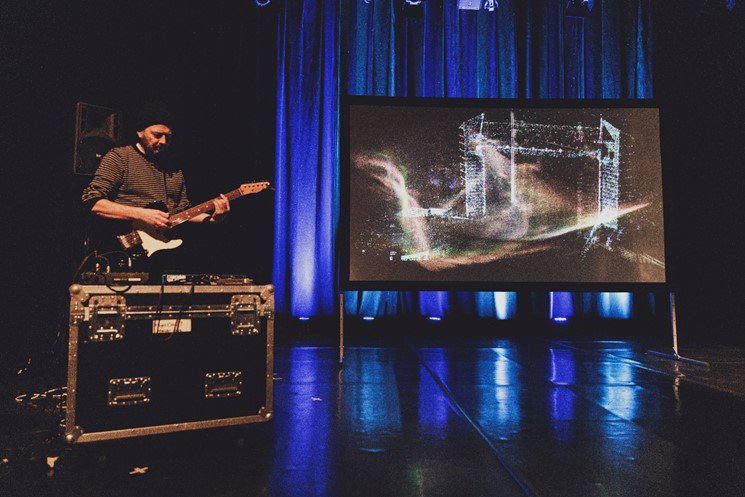 Risky Cities: Flow of Words public performance at the Gulbenkian Theatre. Image by Anete Sooda. Musician performing on stage with image on screen behind