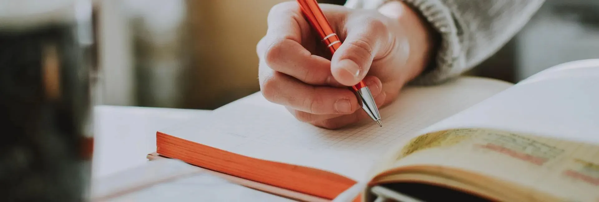 hand holding pen over an open notebook