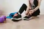 A woman in exercise clothing is tying her trainer shoelaces