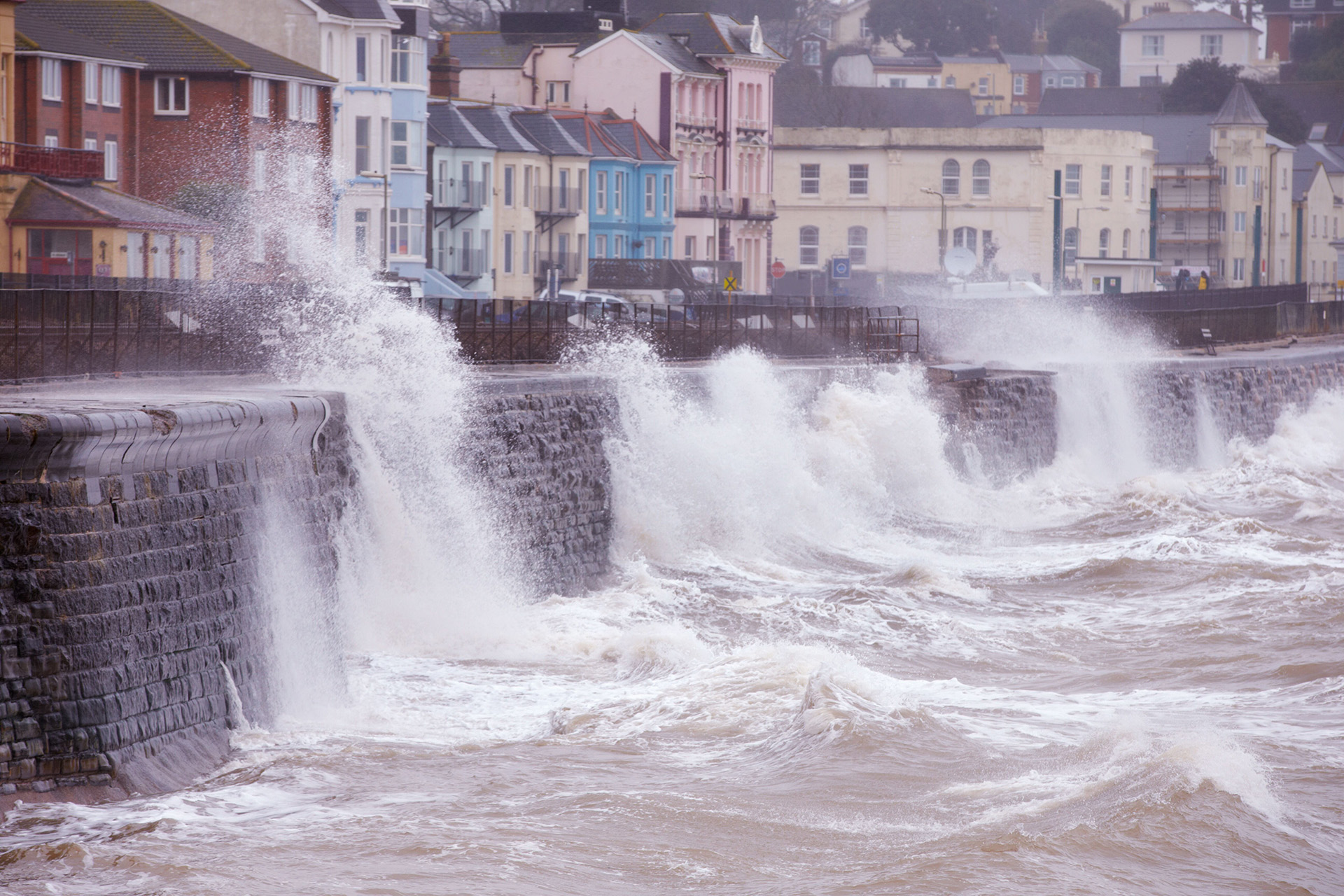 Waves crash against sea defences during a storm in a coastal town