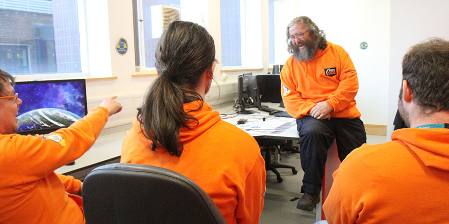 students in a computer science lab, all wearing orange hoodies