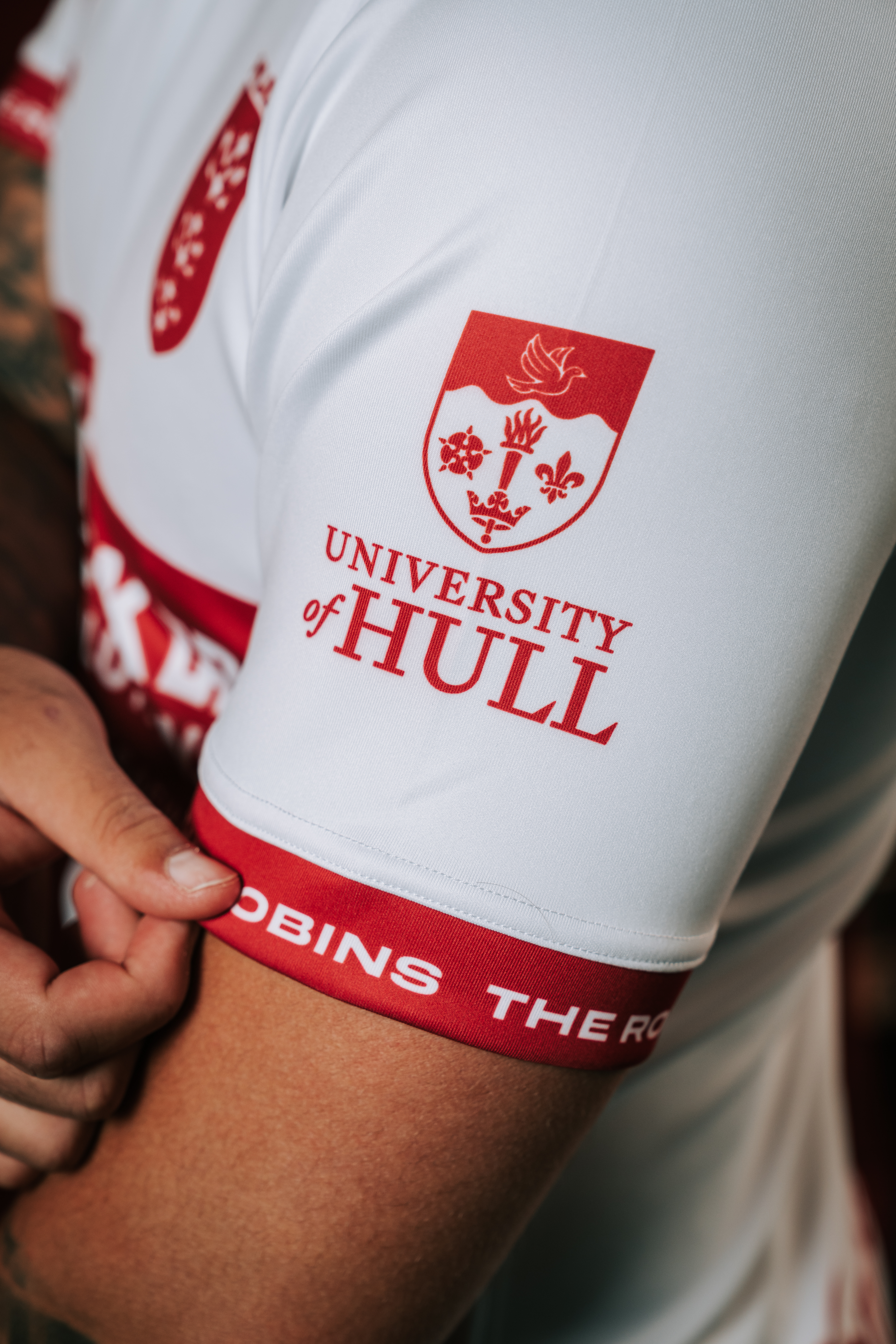 Arm showing sleeve of Hull KR rugby shirt and UoH logo
