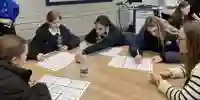 schoolchildren gathered around a table working on a project