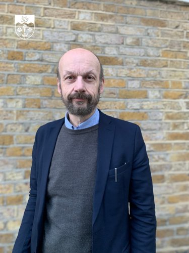 Professor John Craig stood in front of brick wall