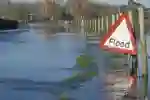 flood sign in front of flooded road