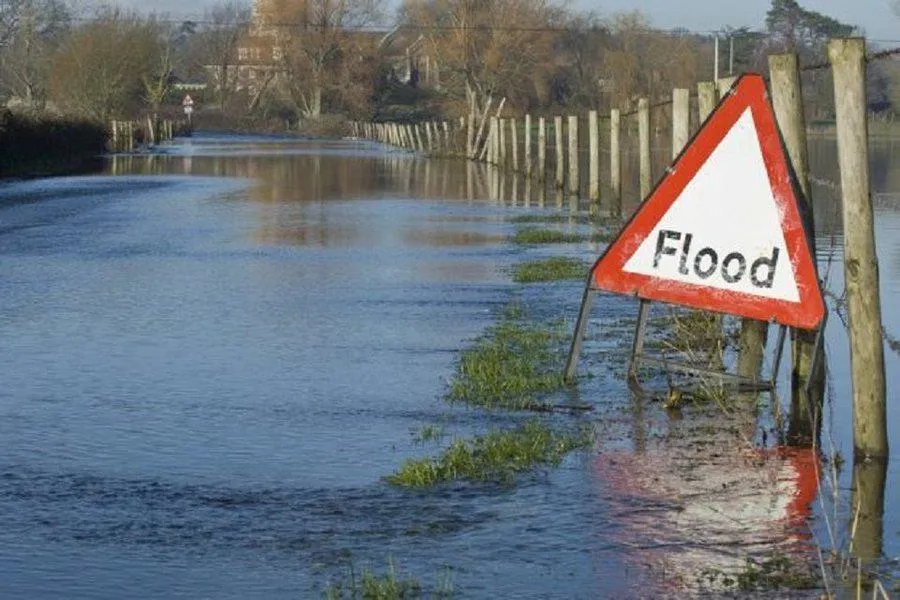 flood sign in front of flooded road