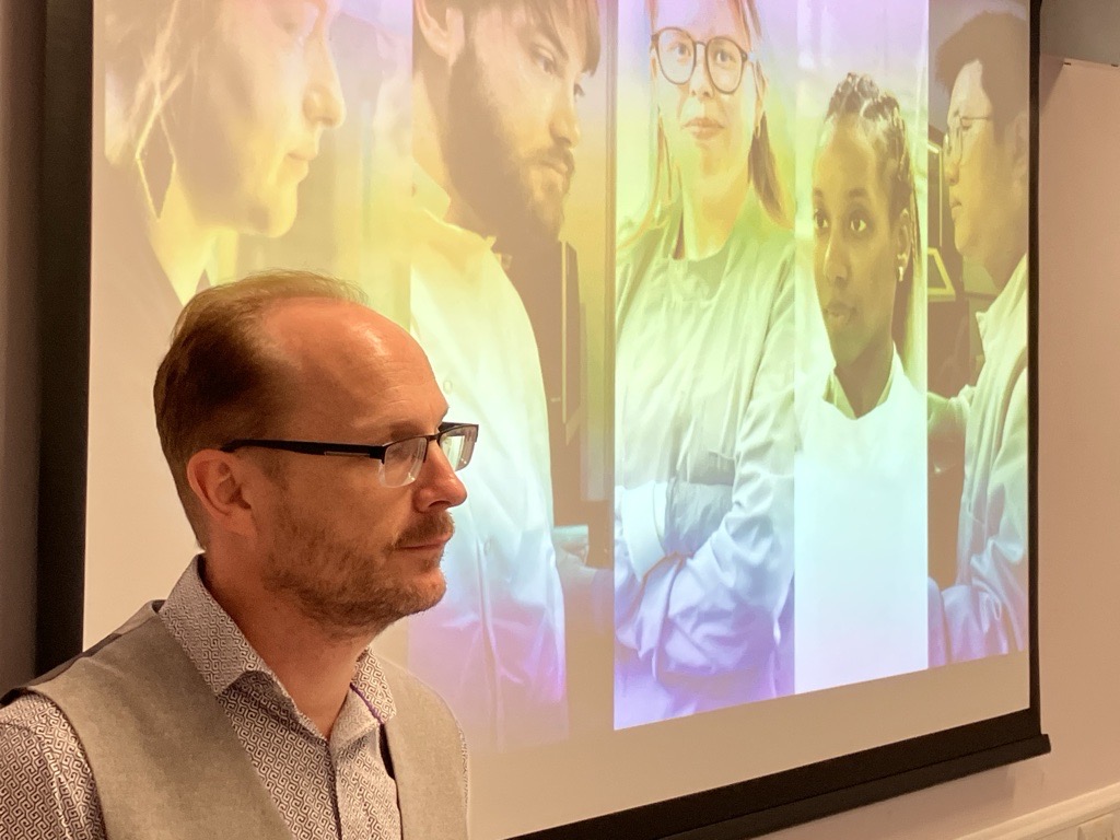 profile shot of man in front of image of researchers