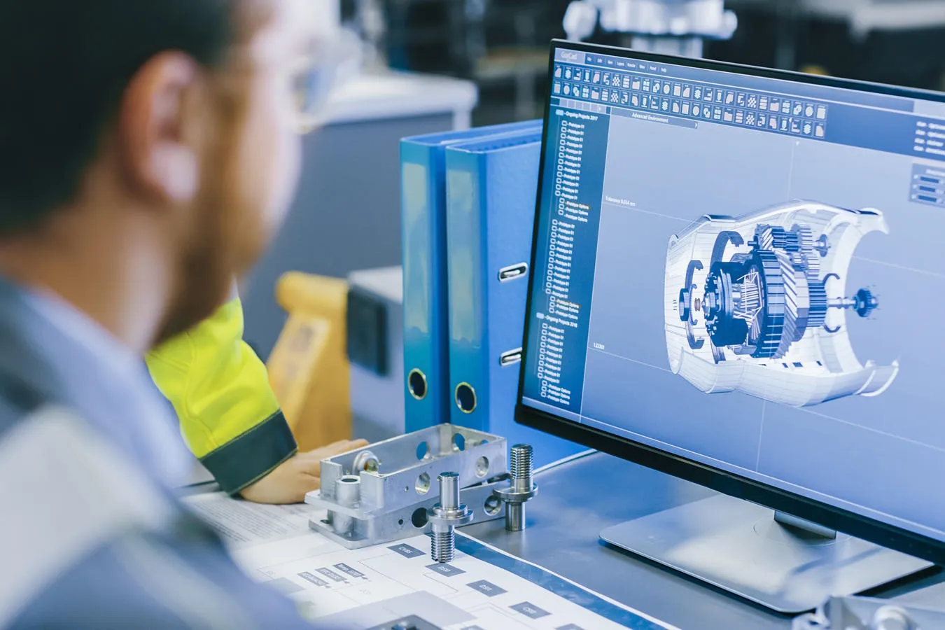 A person in high vis vest looks at a screen showing an engineering model