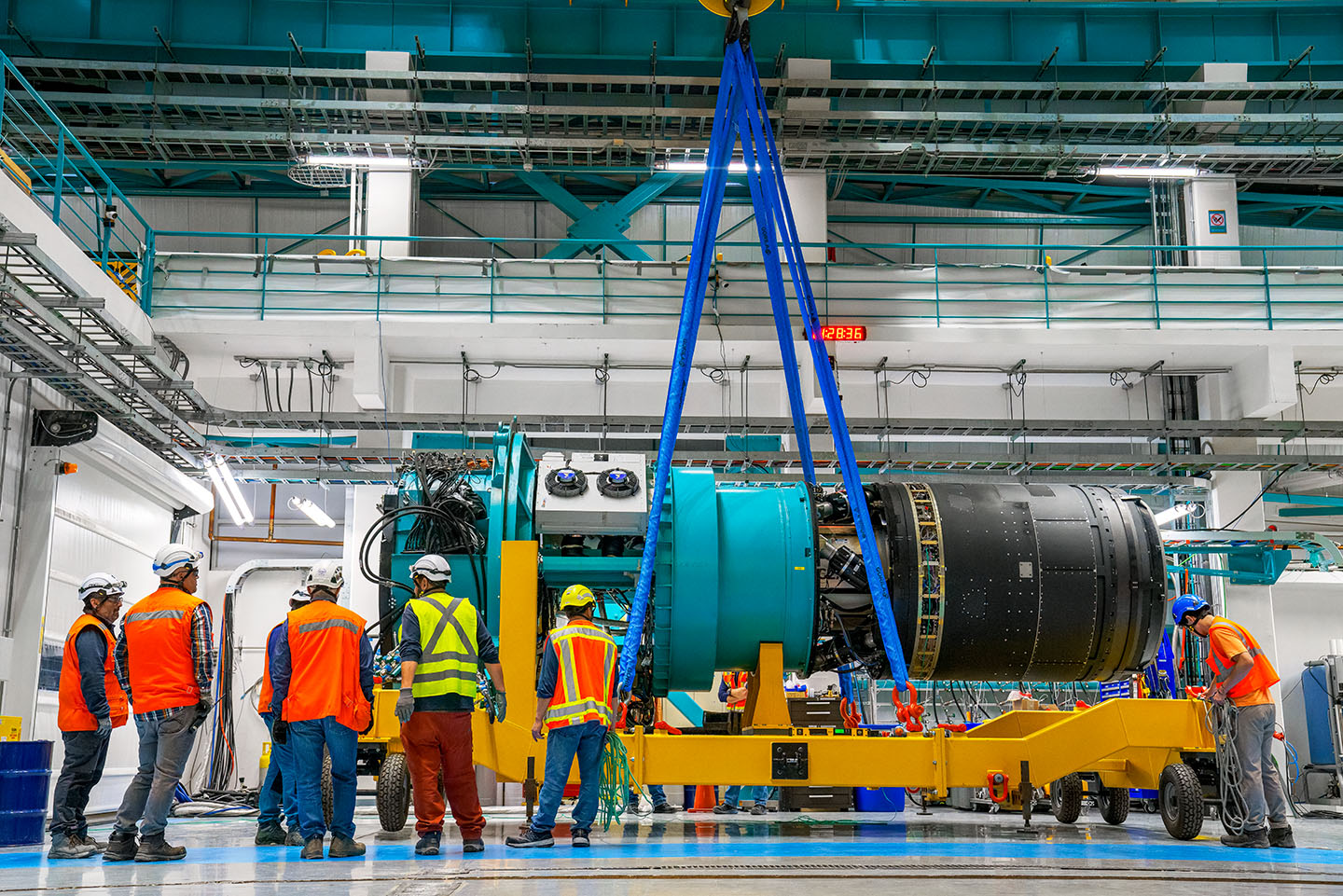 Several workers in high visibility clothing working on large scale scienfic equipment