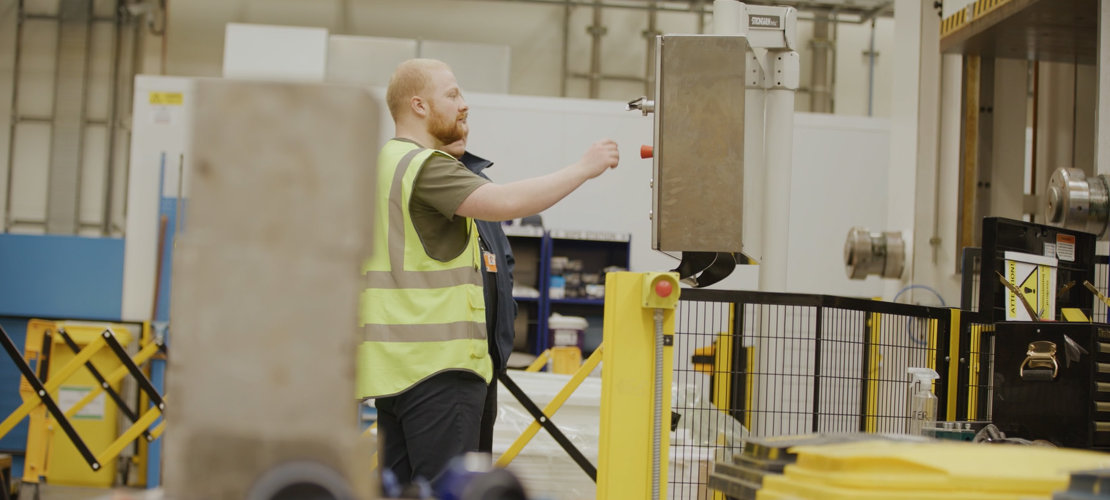 PhD researcher Oliver Morgan-Clague at the Advanced Manufacturing Research Centre man in high viz vest operating machinery in industrial setting