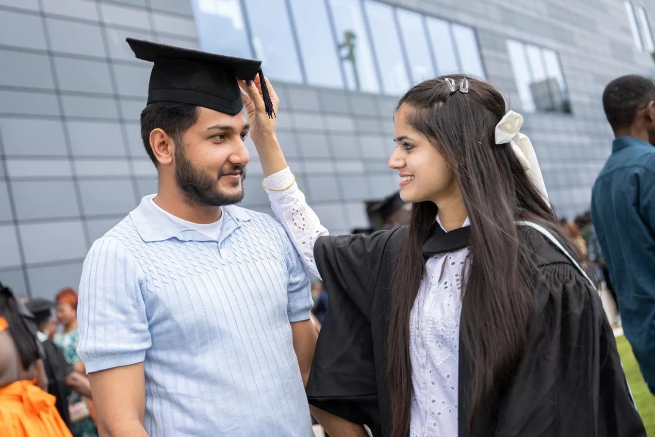 Graduation ceremony woman placing mortar board on man's head