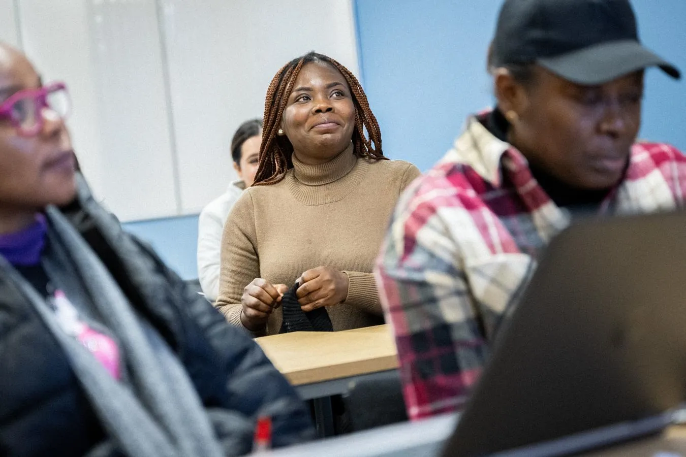 Image show students sitting at desks mid seminar, a woman in focus in the middle is smiling