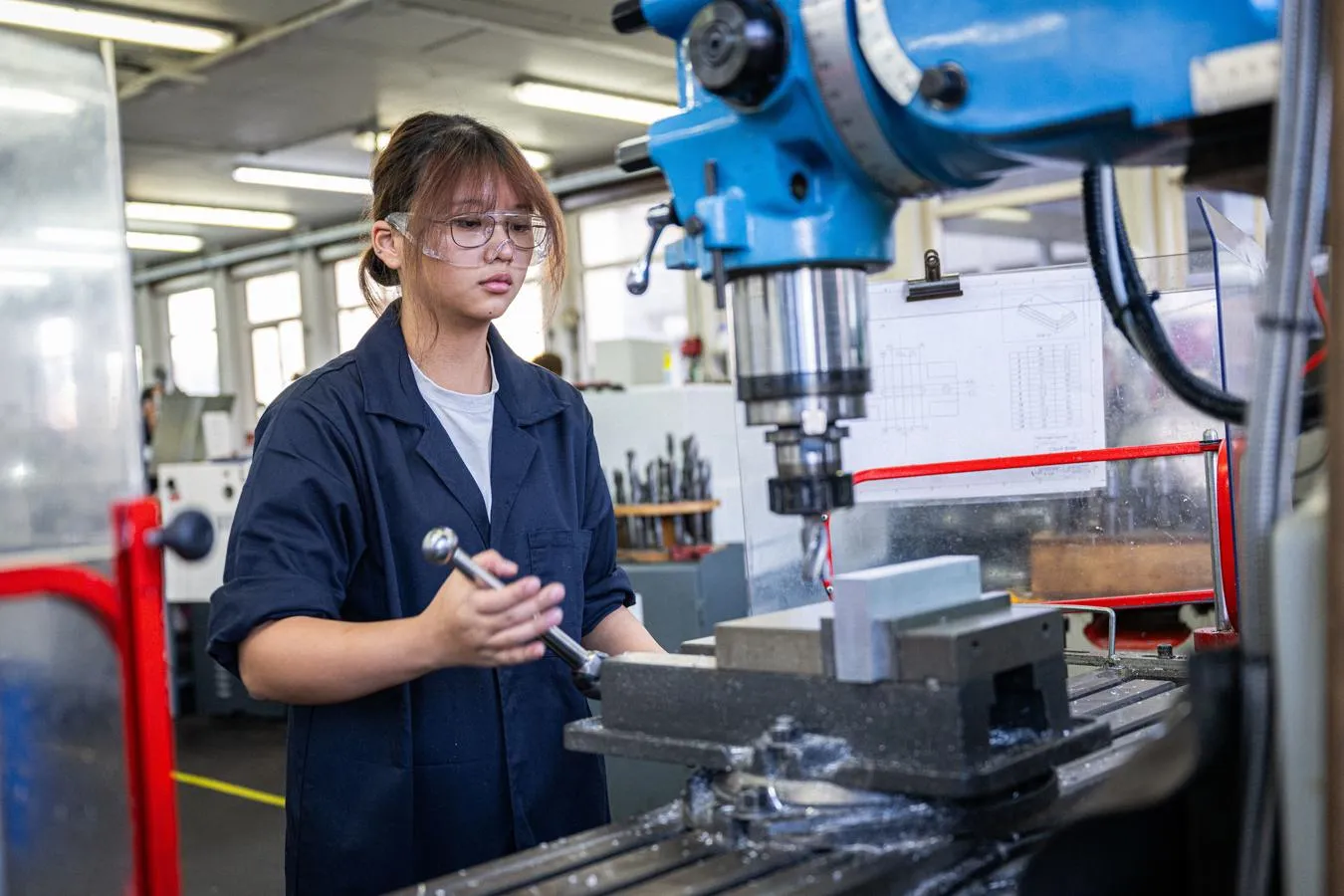 young woman wearing safety glasses operating engineering machinery