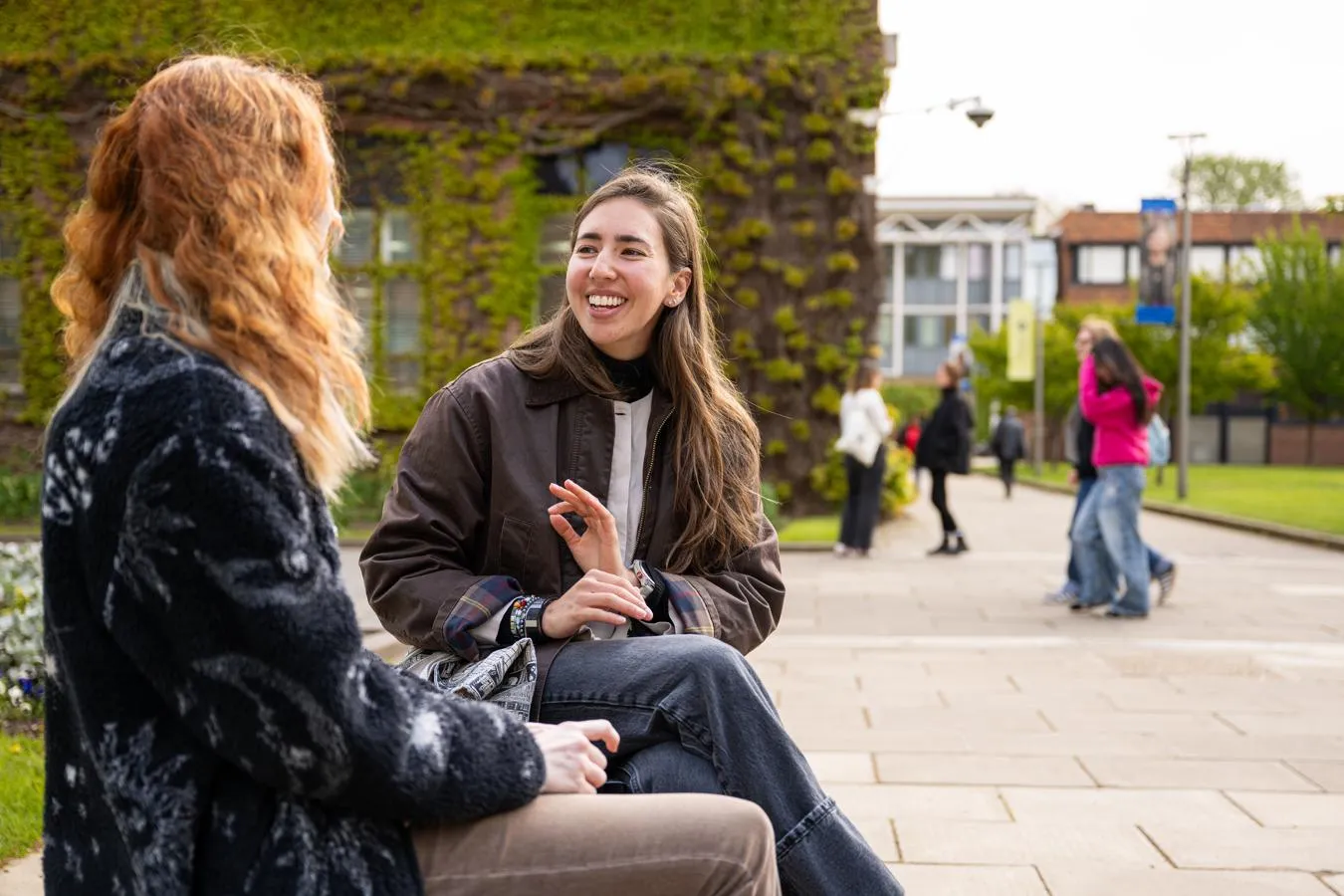 two female students talking on a bench on the university campus