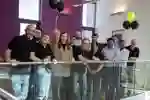 A large group of people stand smiling on a balcony