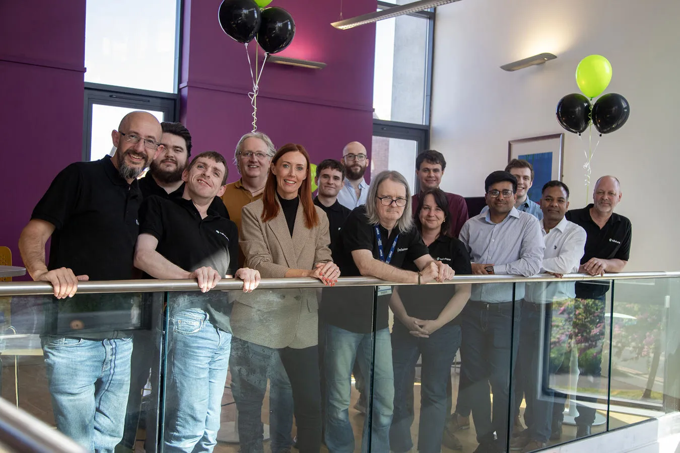 A large group of people stand smiling on a balcony