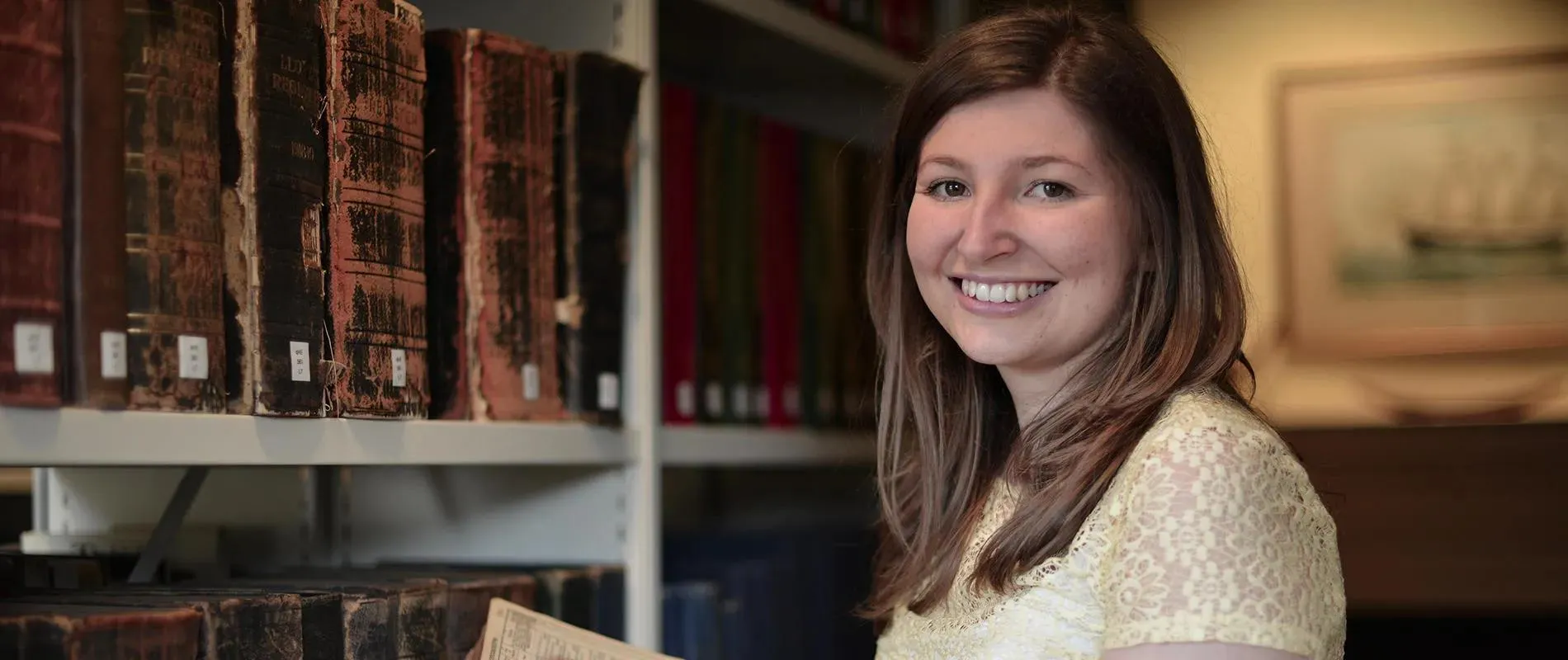 Person stood next to bookcase smiling