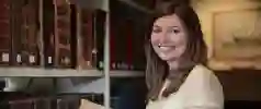 Person stood next to bookcase smiling