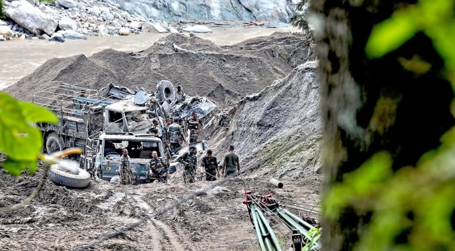 wrecked vehicles in a gulley surrounded by debris left by flooding