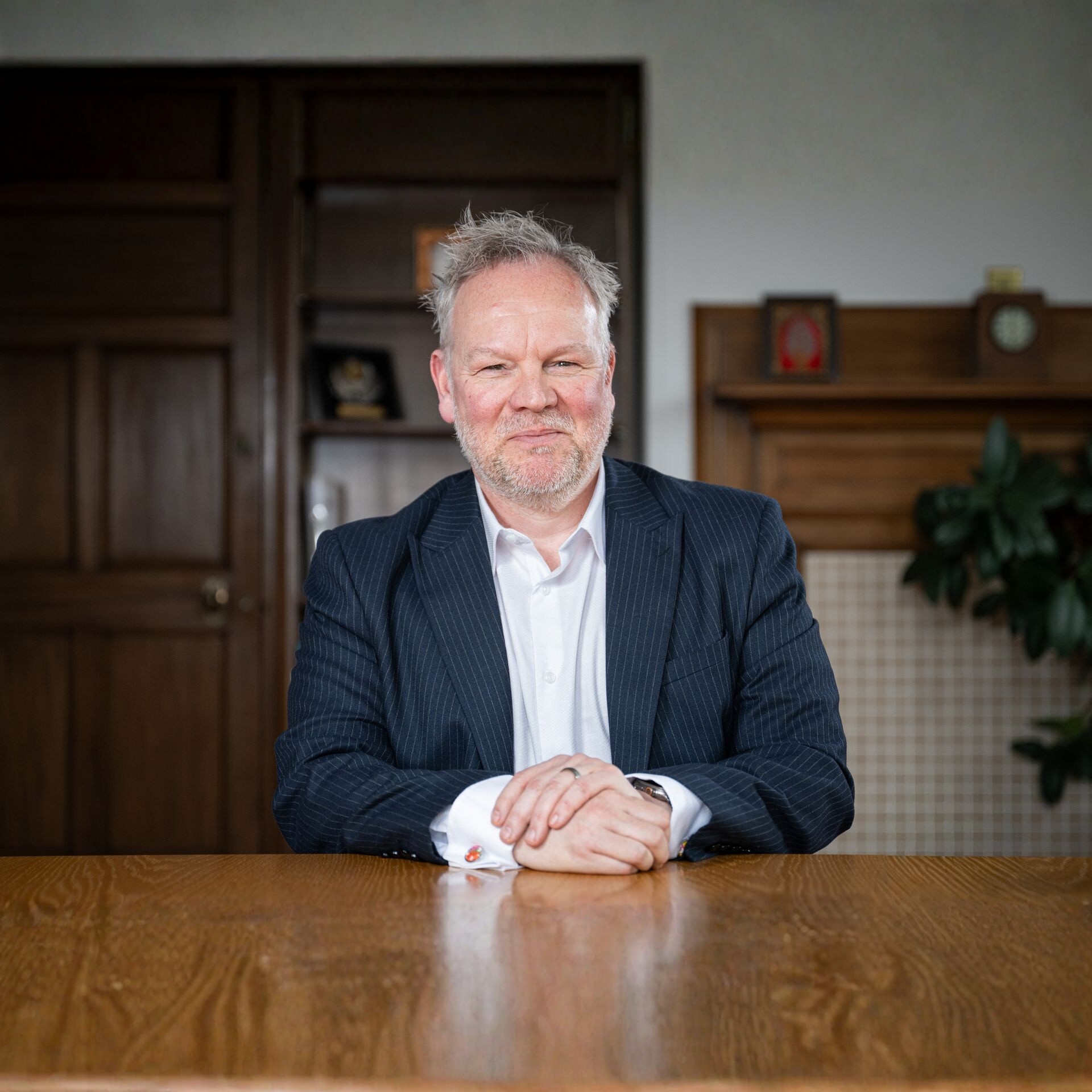 Professor Tom Lawson sat at a desk with arms folded