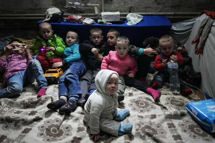 a group of small children on the floor of a bomb shelter looking at the camera