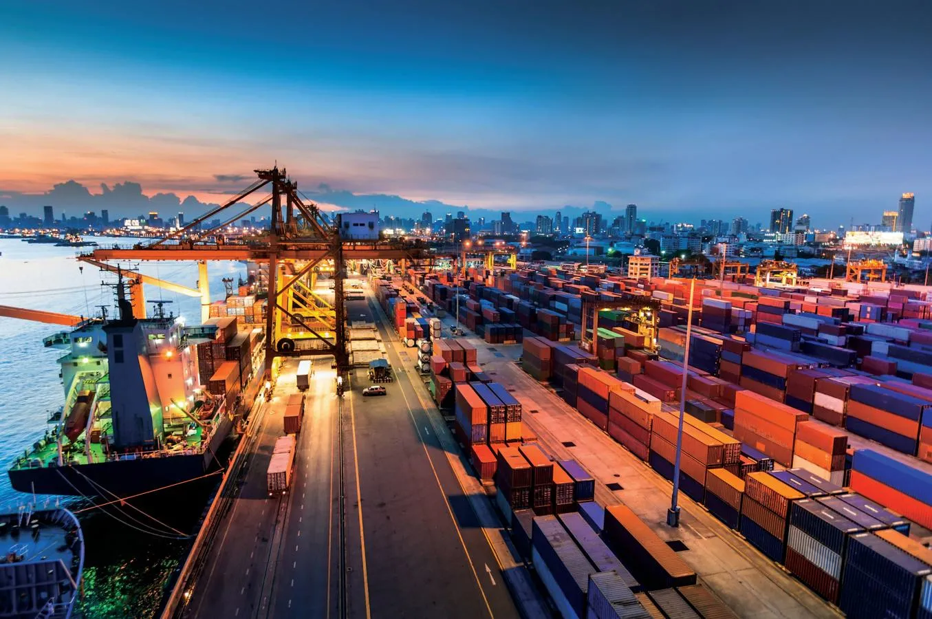 A busy port at night time with a city skyline in the background