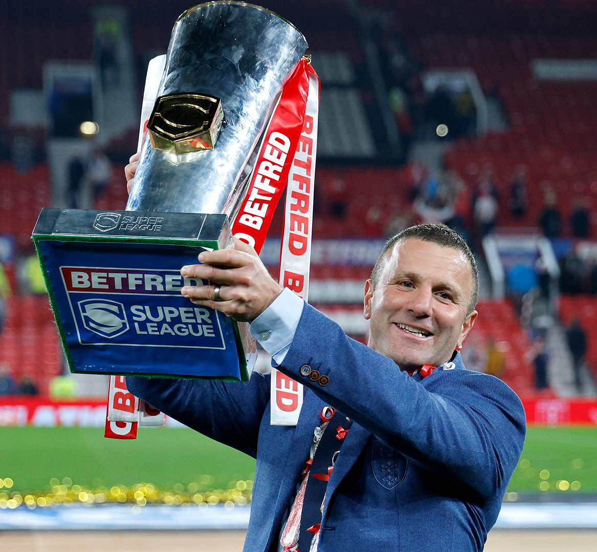 man in blue suit holding trophy aloft