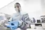 A Wound Innovation Institute researcher handles two petri dishes with blue gloves