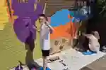 Two schoolchildren paint a colourful mural