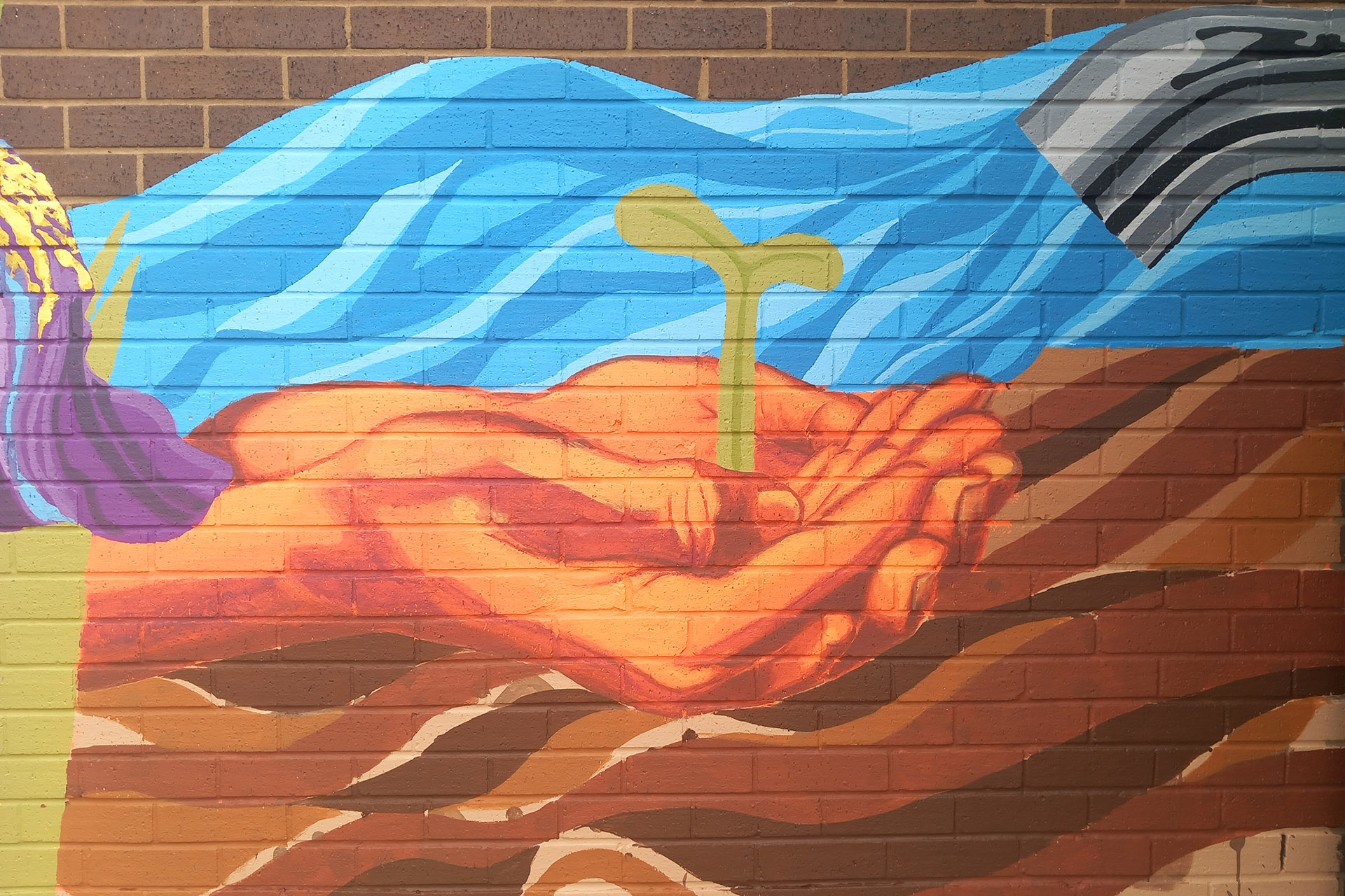A colourful mural shows a hand holding a seedling