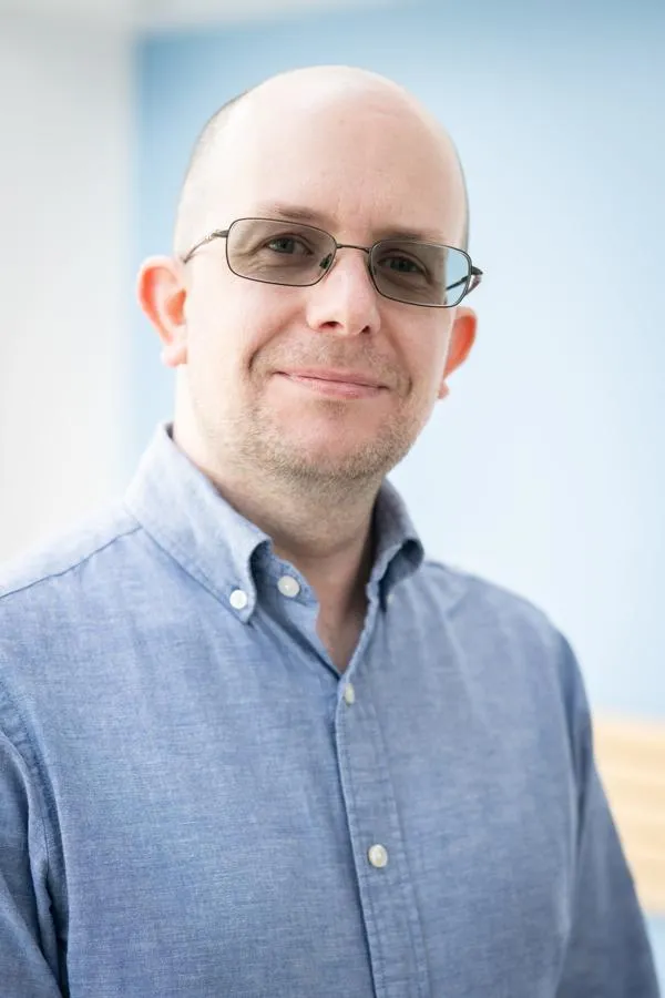 A man dressed in a smart shirt smiling