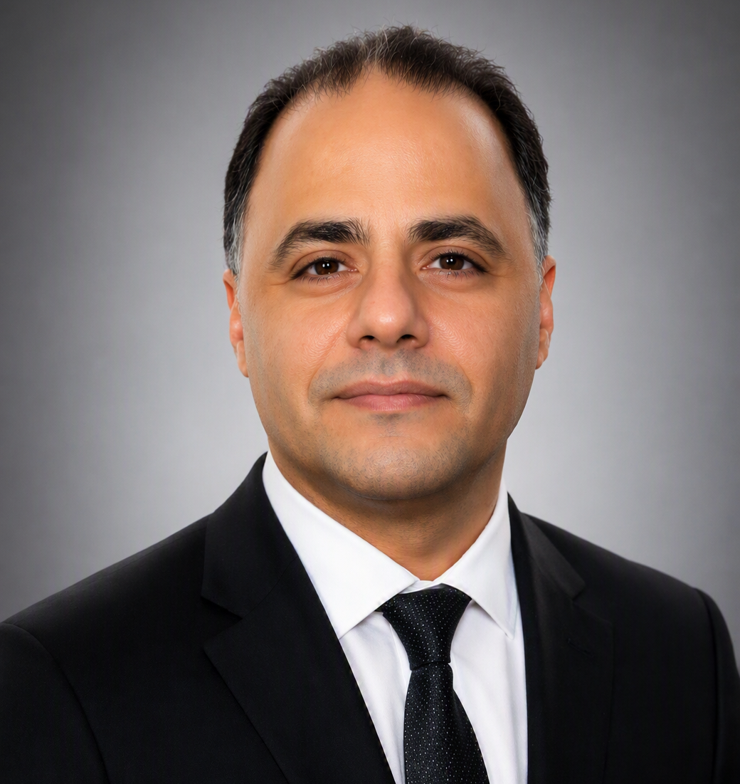 A staff member in a suit smiling at the camera.