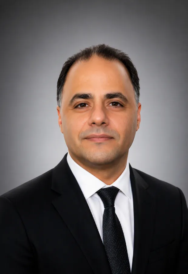 A staff member in a suit smiling at the camera.