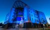 The Allam Medical Building lit up with blue lights at night 