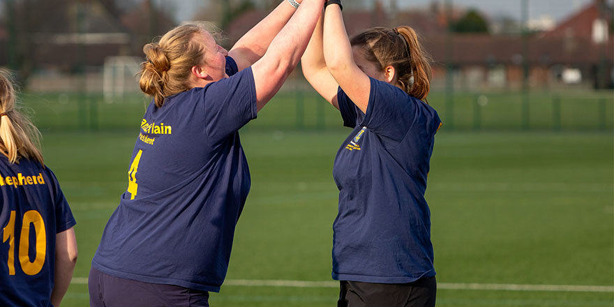two women high-fiving on a sports field