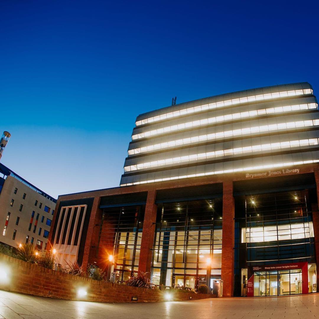 The exterior of the seven-storey Brynmor Jones Library lit up at dusk.