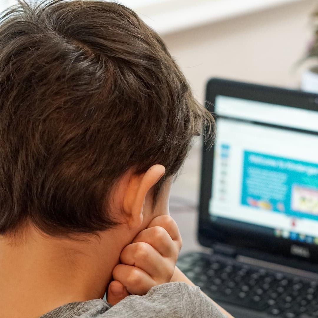A young boy sitting using a laptop