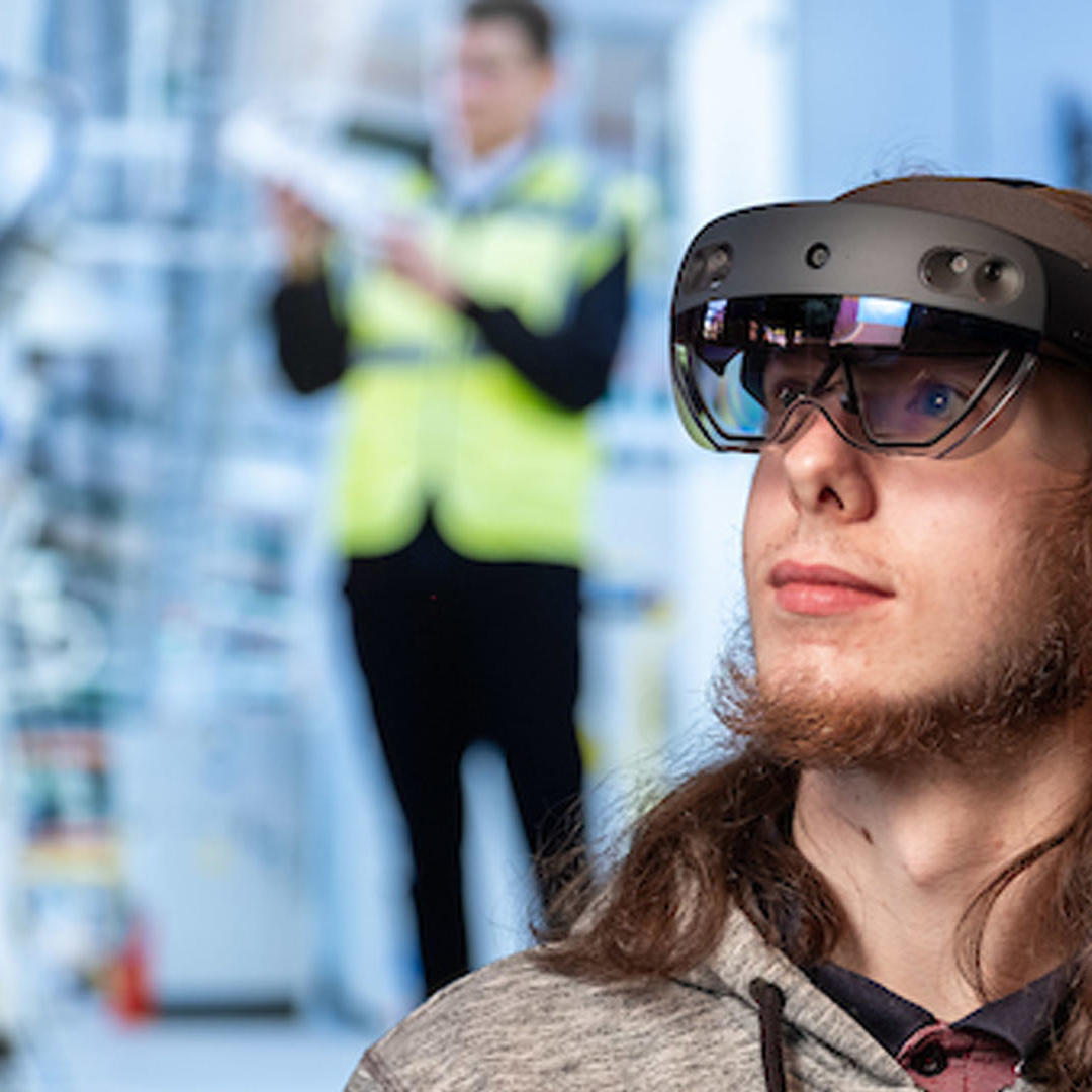 A male student with an alternative reality headset over his eyes