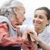 A student nurse smiling at an elderly patient while holding her hand