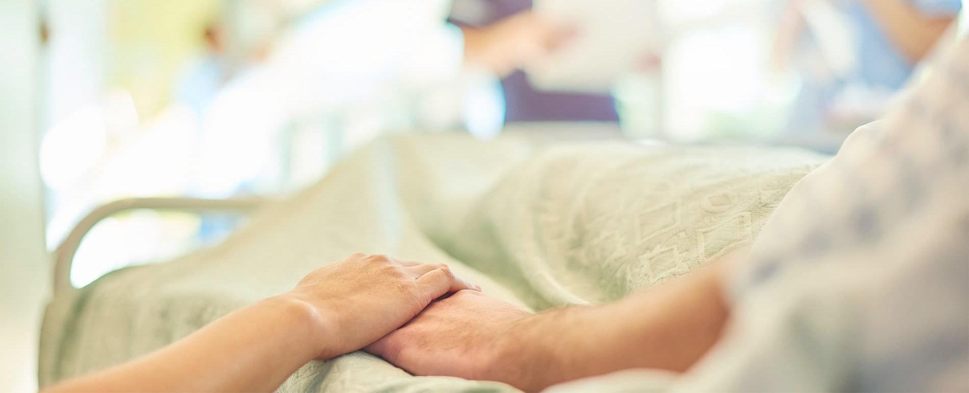Holding hands with a patient in a hospital bed