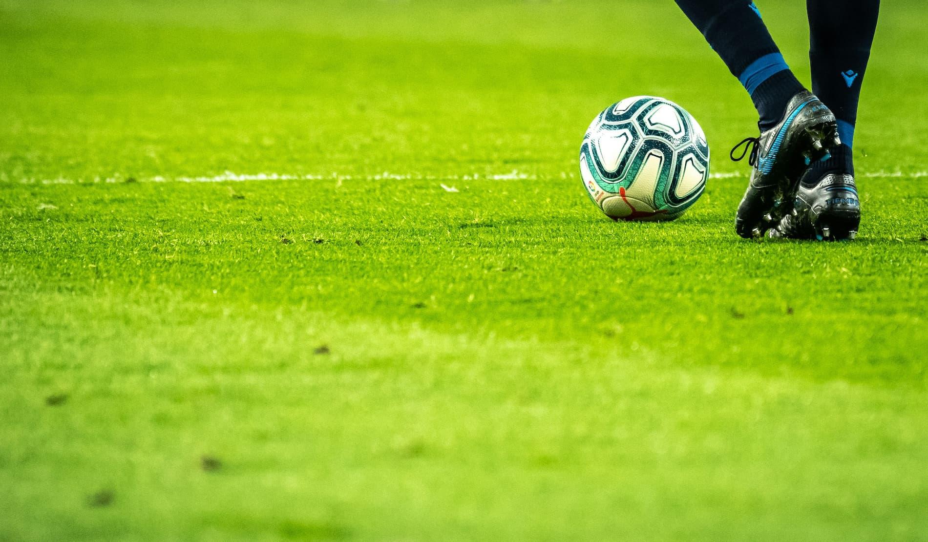 A close up of a football player and ball on the pitch