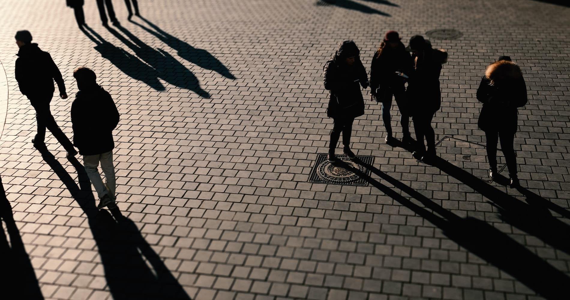 Groups of shadowed people on a cobbled street