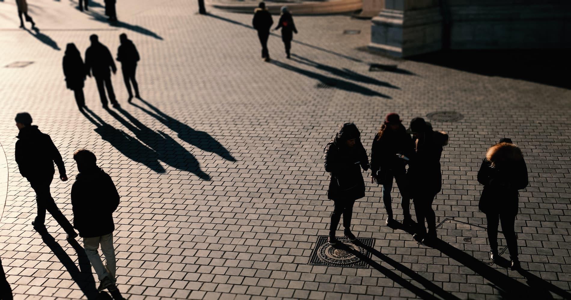 Groups of shadowed people on a cobbled street