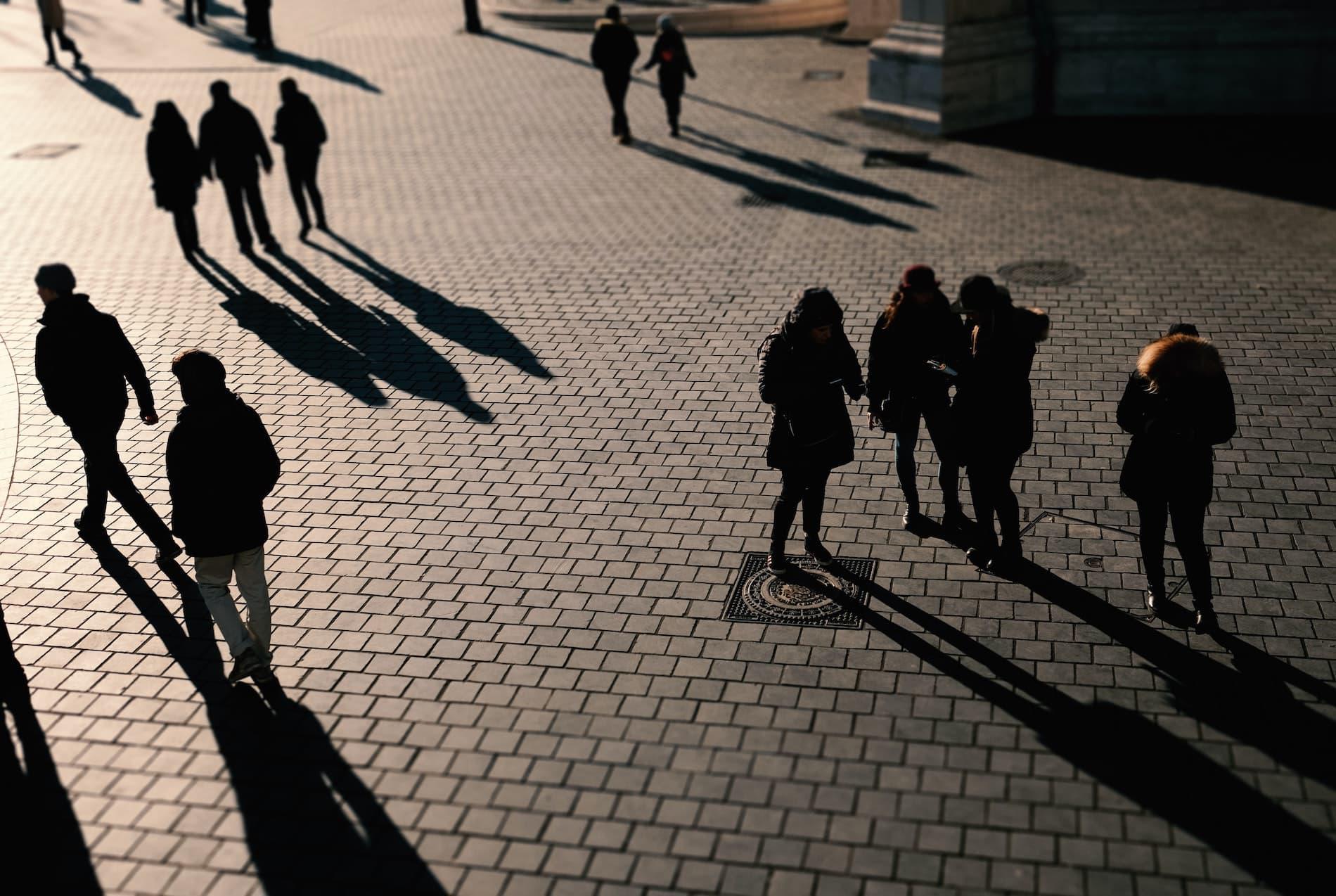 Groups of shadowed people on a cobbled street