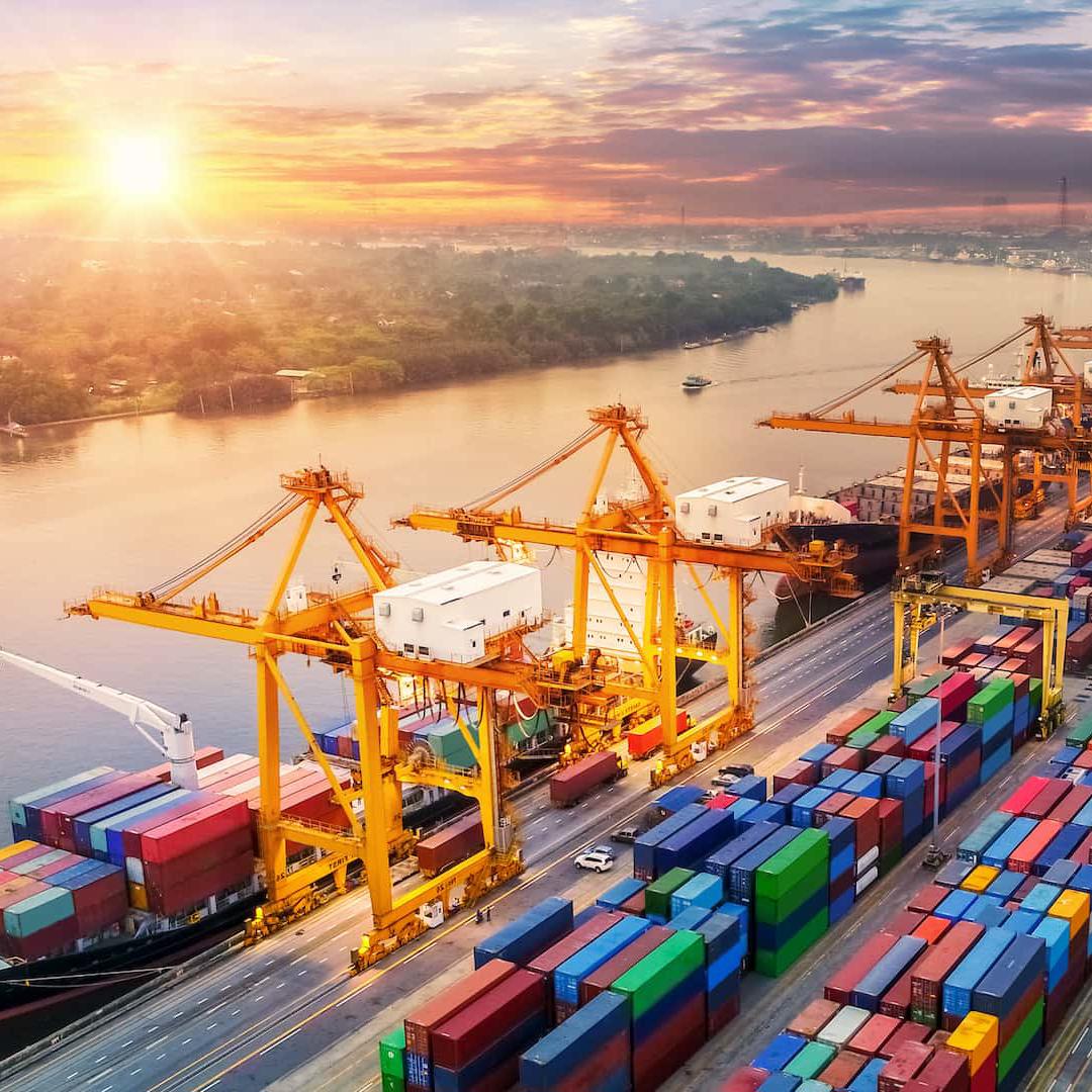 A number of containers are unloaded by cranes from ships moored in a dock