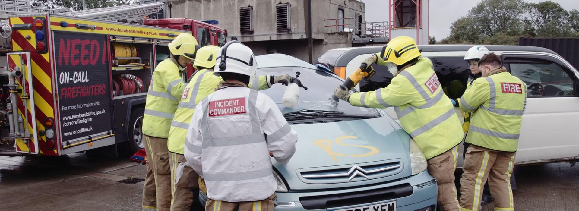 students and firefighters surrounding a simulated car crash