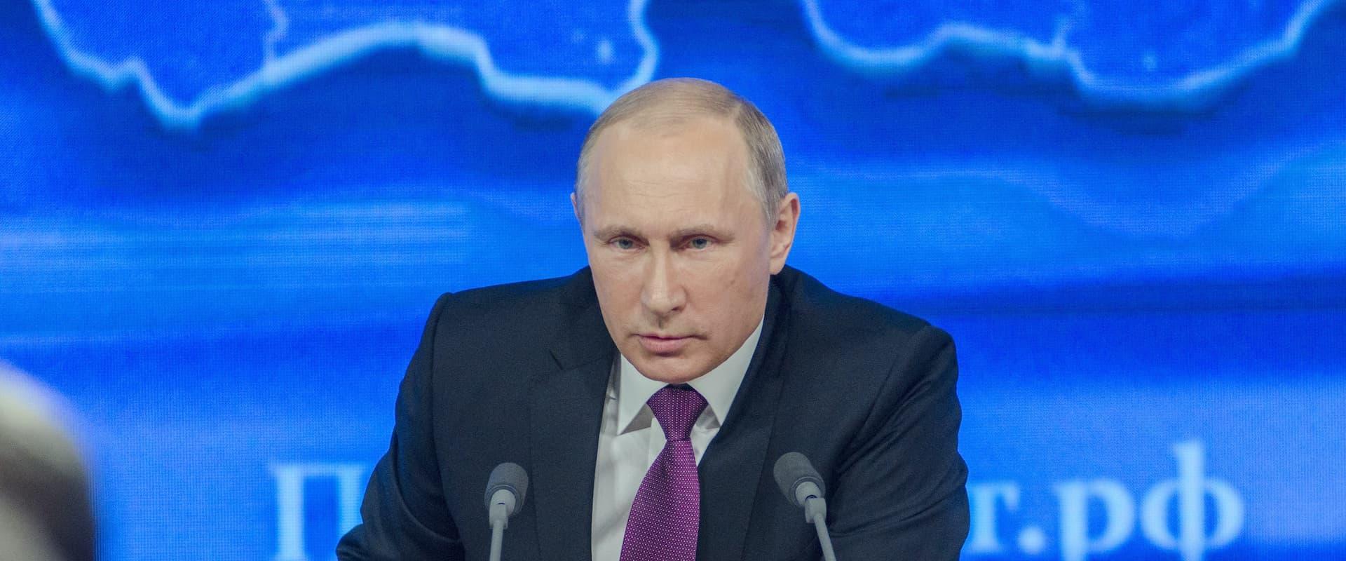Vladimir Putin at a podium, giving a speech