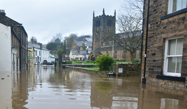 Flood waters lap against houses and businesses around a village green 