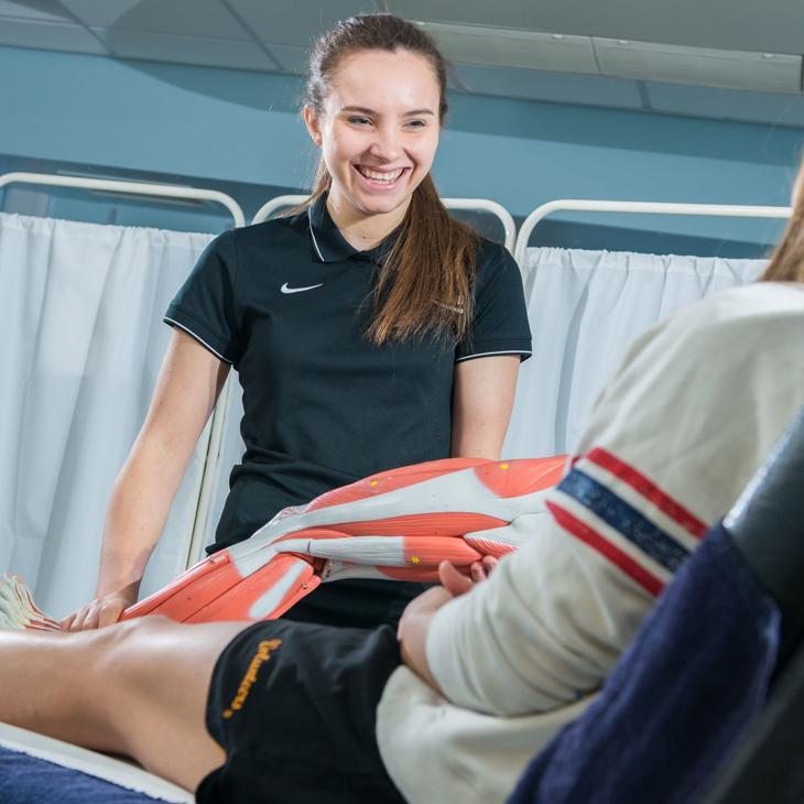 student with muscle diagram with rehabilitation patient